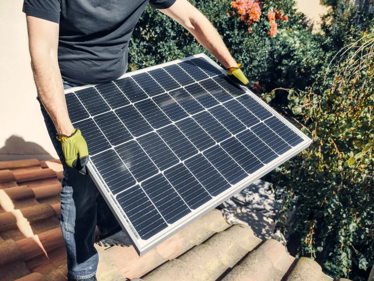 Illustrative Aufnahme eines Monteurs mit einem Photovoltaikmodul.